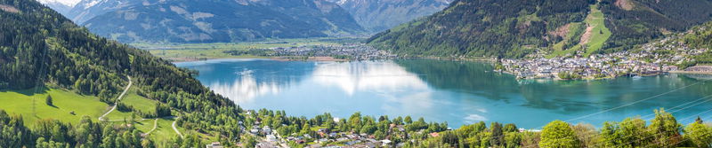 Türkisfarbener Bergsee zwischen bewaldeten Hängen in den Alpen