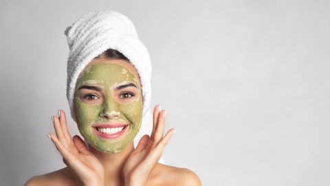 Frau mit Gesichtsmaske und Handtuch auf dem Kopf