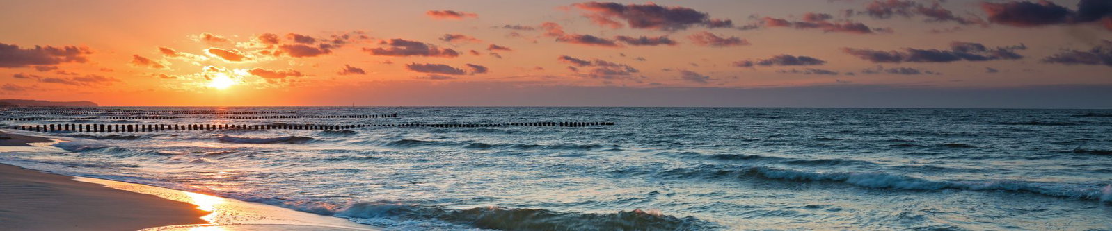 Sonnenuntergang über den Buhnen an einem Ostseestrand