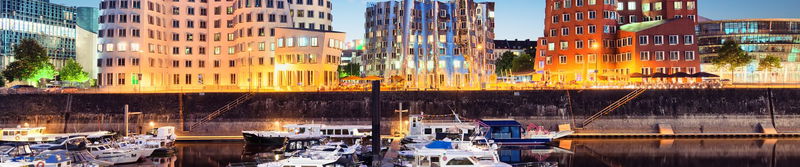 Moderne Gebäude und Boote an einem Hafenbecken im Abendlicht
