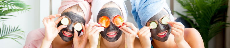 Drei Freundinnen mit Gesichtsmaske und Gurkenscheiben auf den Augen