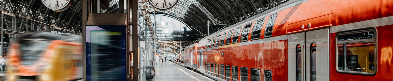 Bahnsteig mit Uhren und roter Eisenbahn