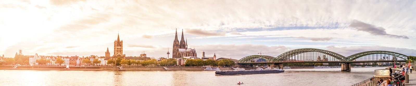 Kölner Dom und Hohenzollernbrücke am Rheinufer im warmen Abendlicht