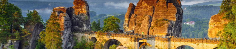 Steinbrücke zwischen hohen Sandsteinfelsen über einem bewaldeten Tal